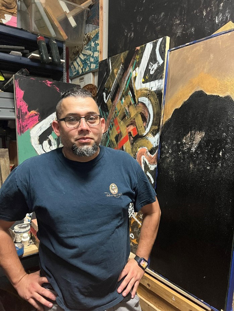 Darwin Arévalo poses next to his work in his East End studio