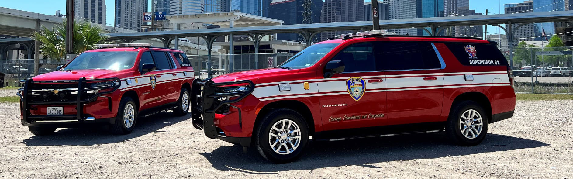 three red SUVs parked in front of Houston Downtown Skyline