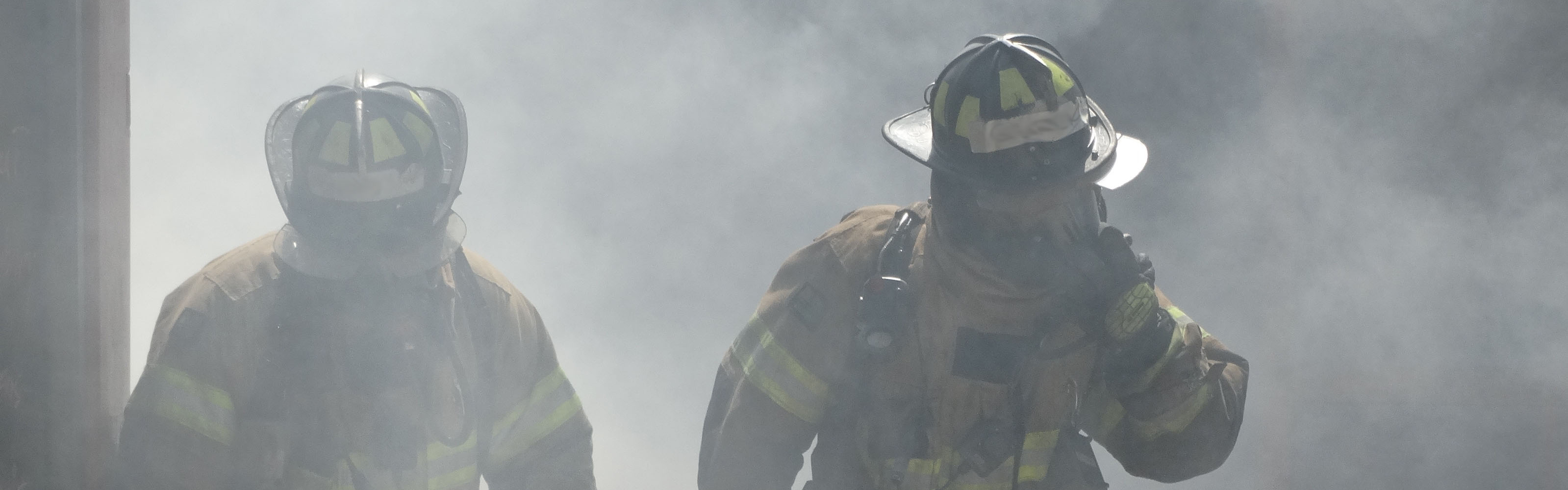 two firefighters walking through smoke in gear