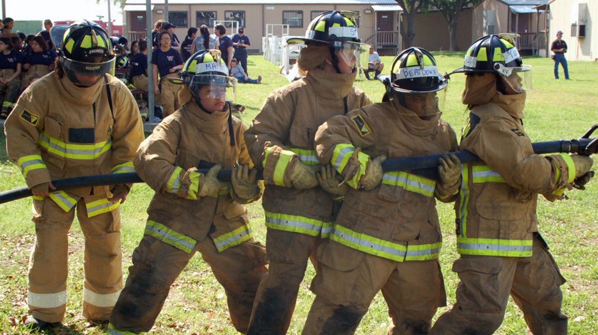 teens holding fire hose in fire gear
